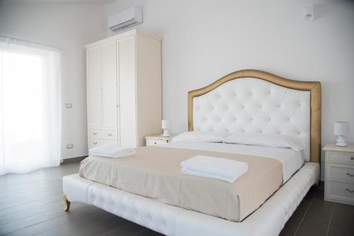 a white bedroom with a large bed with a white headboard at Santo Stefano Club in Praia a Mare