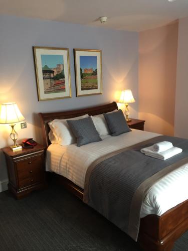 a bedroom with a large bed with two lamps and two beds sidx sidx at Castle Hotel in Tamworth