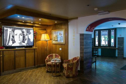 a living room with a tv and a table and chairs at Hotel Posta R.T.A. in Madonna di Campiglio