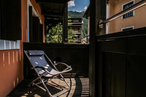 a chair sitting on the porch of a building at Hotel Posta R.T.A. in Madonna di Campiglio