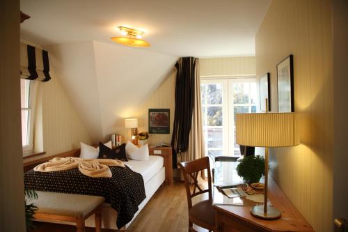 a bedroom with a bed and a desk with a lamp at Romantik Hotel Namenlos in Ahrenshoop