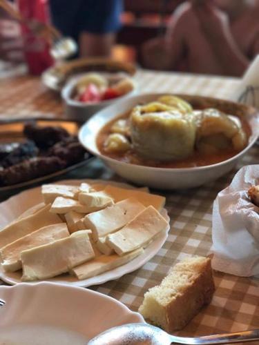 a table with a plate of cheese and a bowl of food at Guesthouse Madzarevic in Pluzine