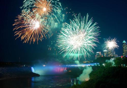 a fireworks display over a river with a city at Tower Hotel at Fallsview in Niagara Falls