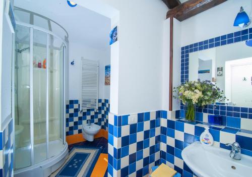 y baño azul y blanco con ducha y lavabo. en Casa Vacanze Li Galli en Sant'Agnello