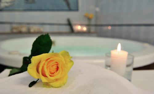una rosa amarilla sentada en una mesa junto a una vela en Hotel Venus, en Gabicce Mare