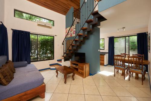 a living room with a staircase and a dining room at Tamarindo Blue Apartments in Tamarindo