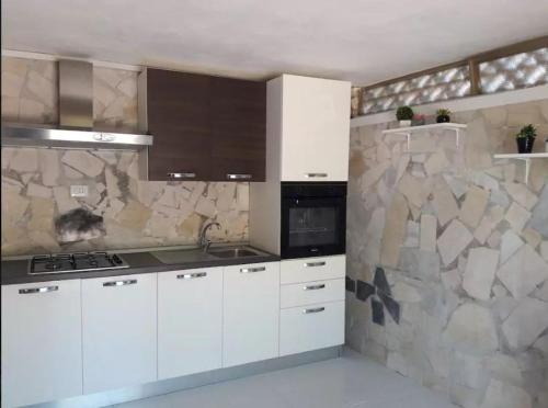 a kitchen with white cabinets and a stone wall at Villa Giovanna in Arenella