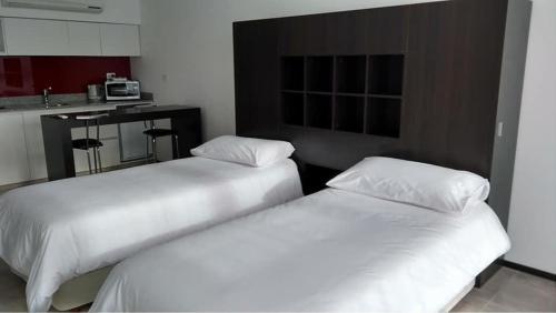 two white beds in a room with a kitchen at Temporal Suites in La Plata