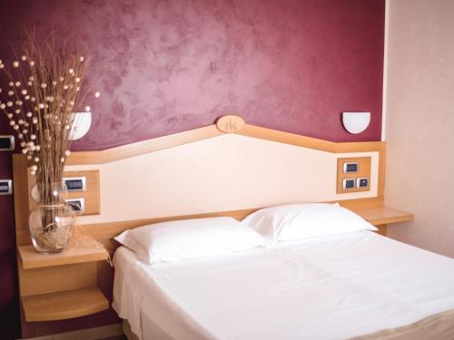 ein Schlafzimmer mit einem weißen Bett und einer lila Wand in der Unterkunft Park Hotel La Grave in Castellana Grotte
