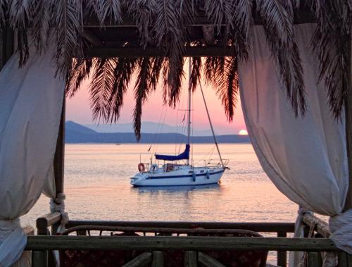 a boat in the water with a sunset in the background at Venus Beach Hotel in Nea Stira