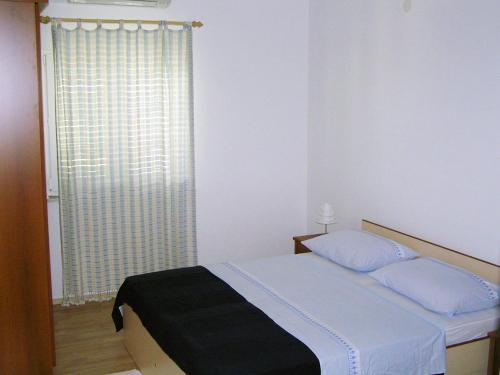 a bedroom with a bed and a window with auliffe at Maglić Apartment in Duće