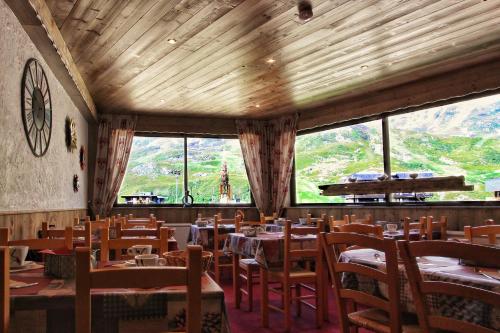 a dining room with tables and chairs and a large window at Hotel Le Pelvoux in Les Menuires