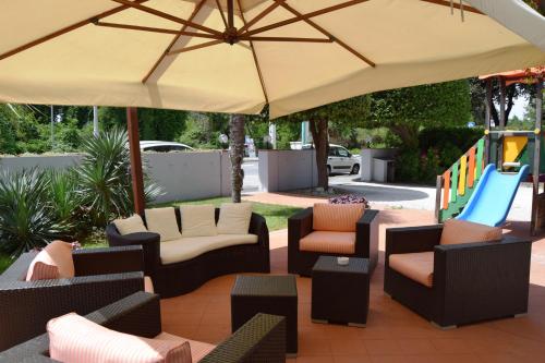 a patio with chairs and an umbrella and a playground at Orchidea Marina in Tirrenia