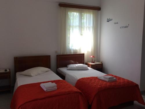 a bedroom with two beds with red sheets and a window at Studios Stefani in Petra