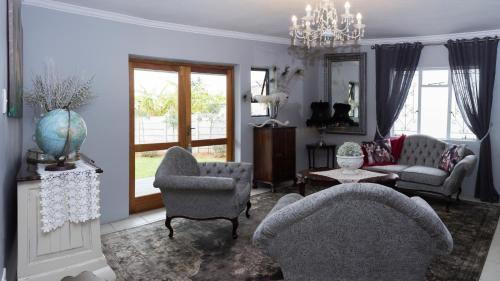 uma sala de estar com duas cadeiras e um sofá em Villa Petit em Jeffreys Bay