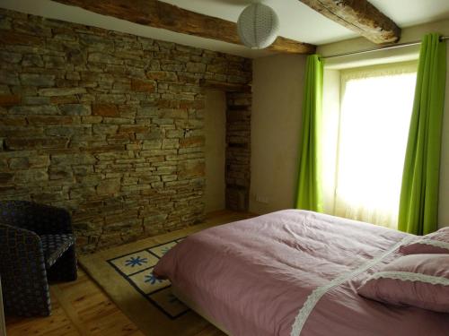 een slaapkamer met een bed en een bakstenen muur bij Le Relais in Saint-Sauveur-la-Pommeraye