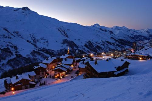 a village in the snow at night with mountains at Hotel Le Pelvoux in Les Menuires