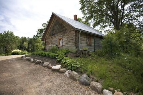 an old wooden house with a row of rocks around it at Dzirnavkalns in Cesvaine