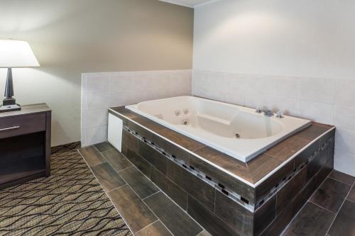 a bath tub in a room with a table and a lamp at Baymont by Wyndham Auburn in Auburn