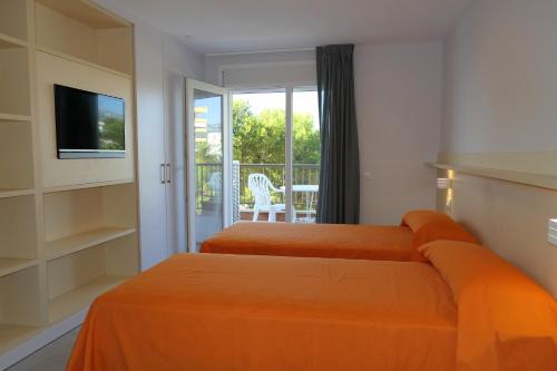 two beds with orange sheets in a room with a balcony at Rentalmar Miami Palace Plus in Miami Platja