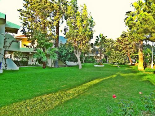 a yard with green grass and trees and a building at Filerimos Village Hotel in Ialyssos