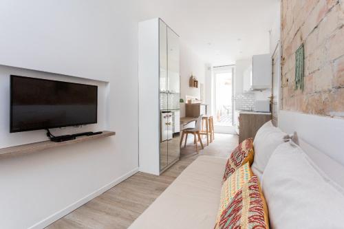 un salon avec un canapé et une télévision sur un mur dans l'établissement Le Petit Nicolas, à Montpellier