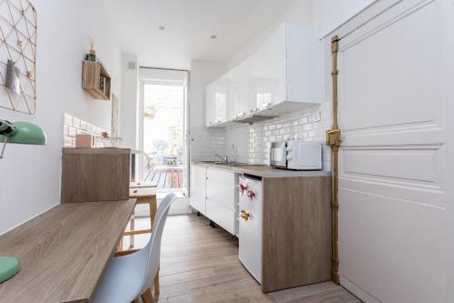 une cuisine avec des armoires blanches et un comptoir en bois dans l'établissement Le Petit Nicolas, à Montpellier