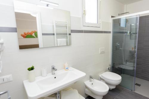 a white bathroom with a sink and a toilet at Innsud in Nardò