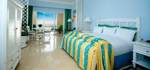 a bedroom with a large bed and a living room at Suites at PB Rose' Resort and Spa Cabo San Lucas in Cabo San Lucas