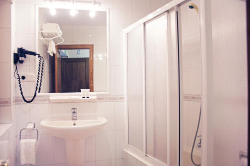 a white bathroom with a sink and a shower at Apartamentos La Lula in Cudillero