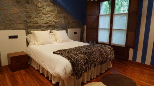 a bedroom with a large bed with a stone wall at Apartamentos Lagos de Saliencia in Saliencia