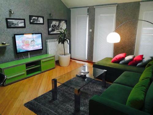 a living room with a green couch and a television at Vip apartment Beograd in Belgrade