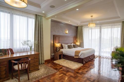 a hotel room with a bed and a desk and windows at GemSuites Riverside Serviced Apartments and Hotel, Nairobi in Nairobi