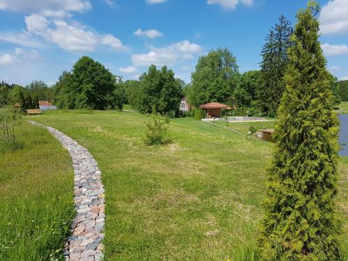 a stone path in a field next to a lake at Meždzirnas Country House & SPA in Kabile