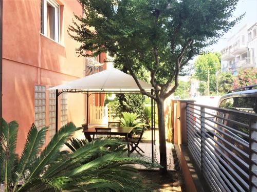 eine Terrasse mit einem Tisch, einem Sonnenschirm und einem Baum in der Unterkunft Miramare Beach Apartment in Rimini