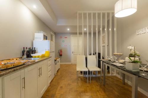 una cocina con armarios blancos y una mesa con sillas. en Brivaldo Guest House, en Angra do Heroísmo