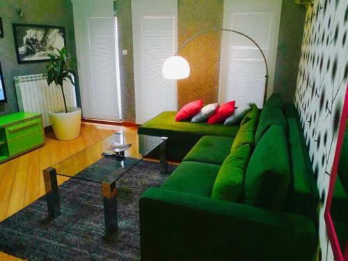 a living room with a green couch and a table at Vip apartment Beograd in Belgrade