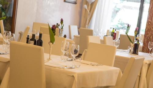 a dining room with white tables and chairs with wine bottles at Hotel Aurora in Lido di Jesolo
