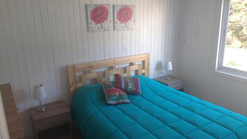 um quarto com uma cama azul com duas almofadas em Cabañas Felipe em Pichilemu