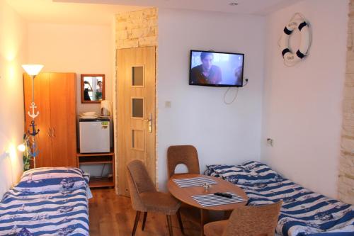 a room with two beds and a table and a tv at Dom wczasowy Ewa in Jastrzębia Góra