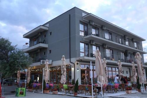 a building with chairs and umbrellas in front of it at Hotel Agapi Mamaia in Mamaia