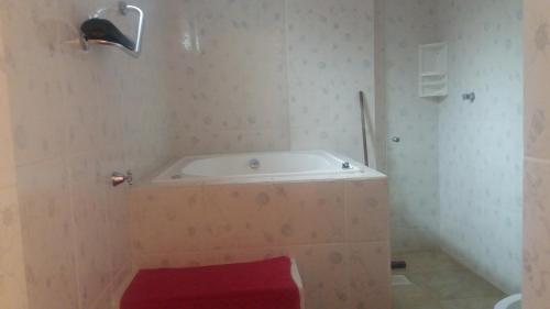y baño con bañera y taburete rojo. en Pousada Delícias do Mar, en Pirenópolis
