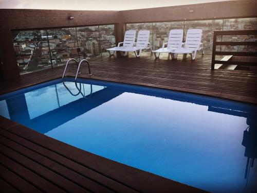 a swimming pool with chairs and a view of a city at Serema Palace Hotel in Lavras