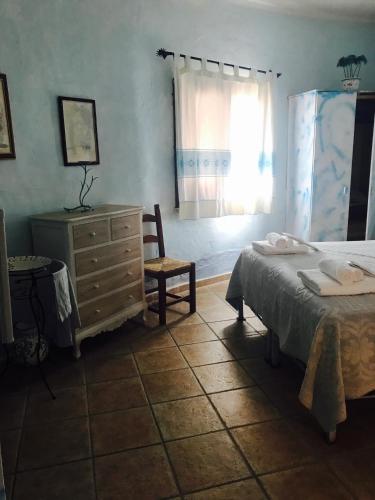 a bedroom with a bed and a dresser and a chair at Il Nuraghe del lago Coghinas in Oschiri