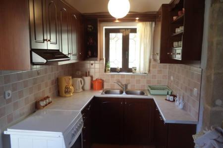 a kitchen with brown cabinets and a sink and a window at Kavousi Traditional Home in Falasarna