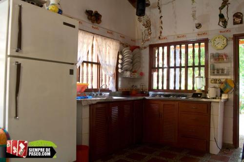 a kitchen with a white refrigerator and some windows at Hostal Roldan in Coveñas