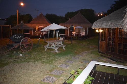 a group of huts with a picnic table at night at Hotel Casa de Piedra in Coquimbo