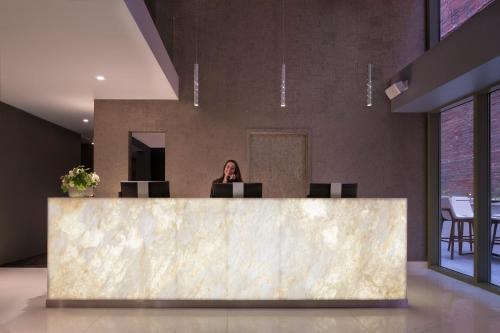 a woman standing in front of a marble counter top at Hotel Via in San Francisco