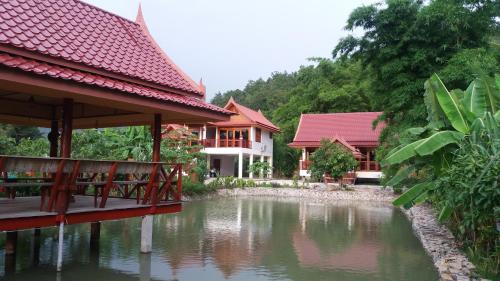 a house with a pond in front of a building at Jasmin Resort in Mae Hong Son