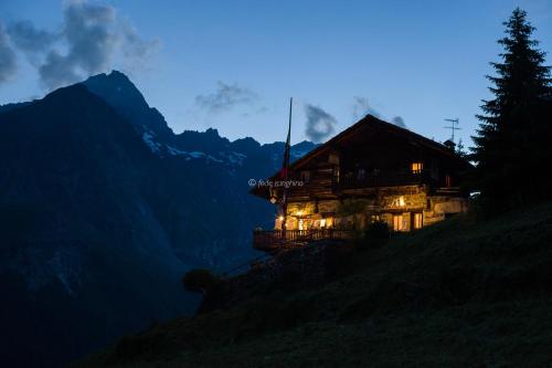 une maison sur le flanc d'une colline la nuit dans l'établissement Rifugio Guide Frachey, à Saint-Jacques